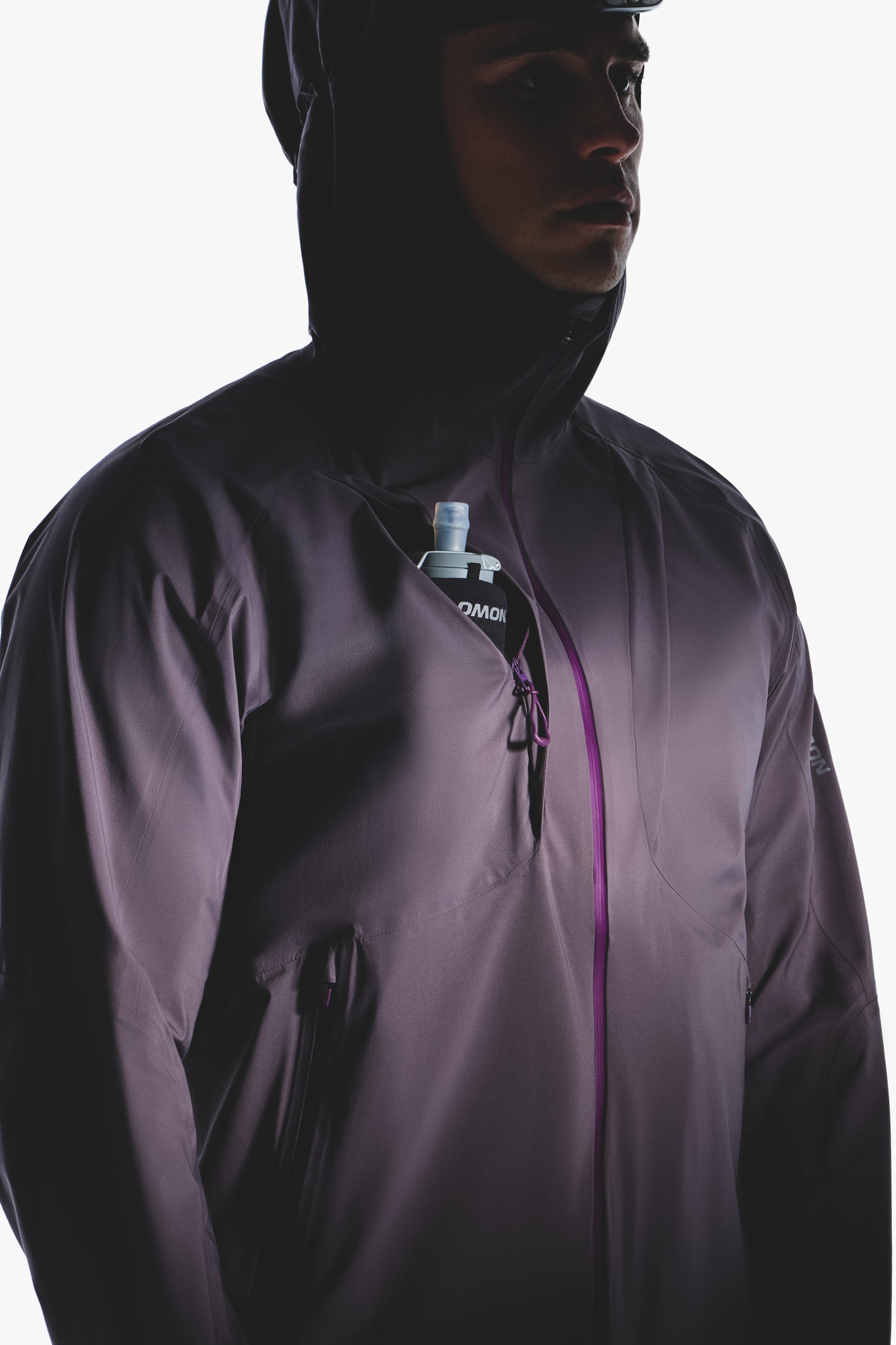 Close-up of the Salomon men's Autumn/Winter 2026 purple hooded jacket chest pocket holding a soft flask.