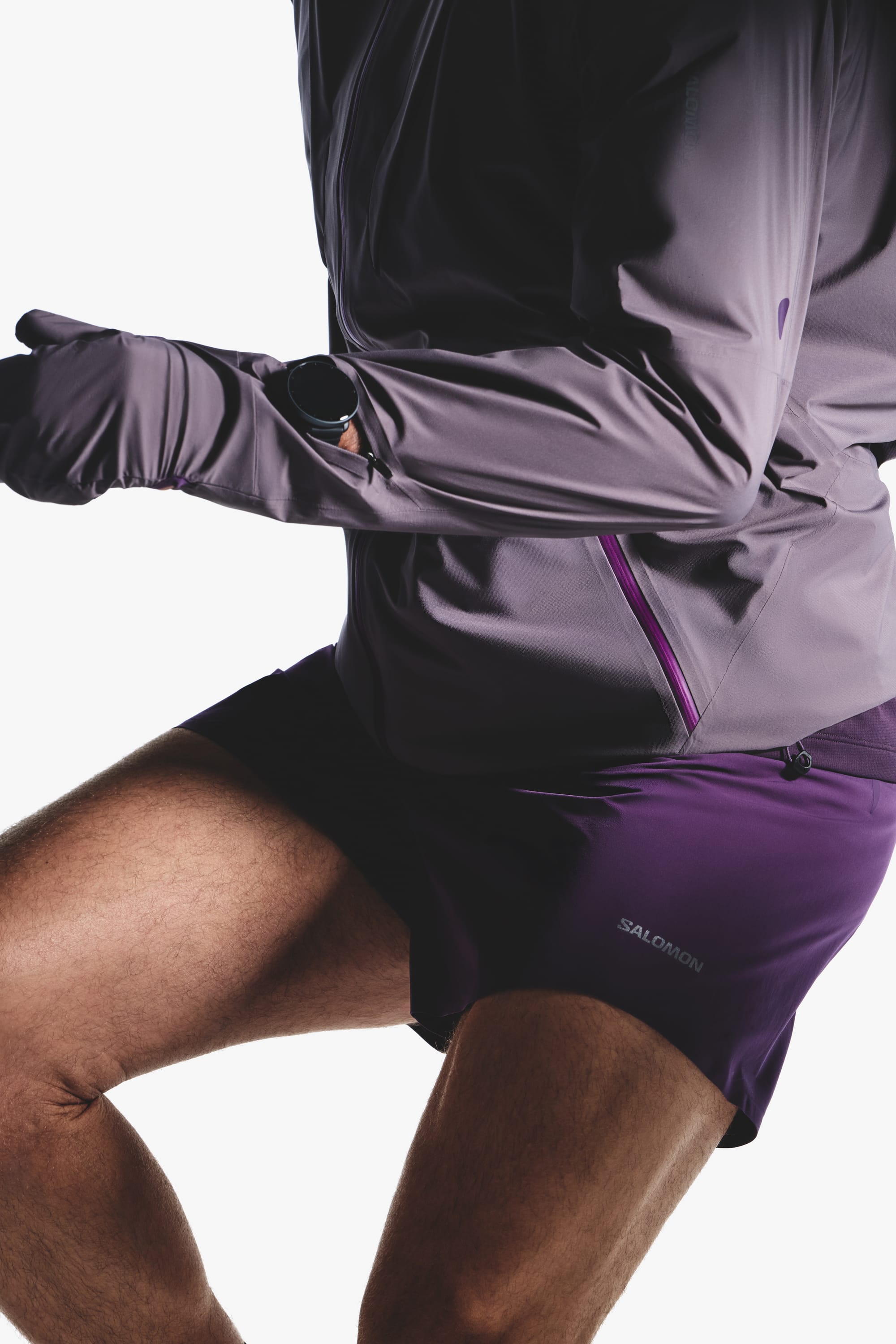 Action detail of the Salomon men's Autumn/Winter 2026 purple jacket, gloves, watch, and shorts.