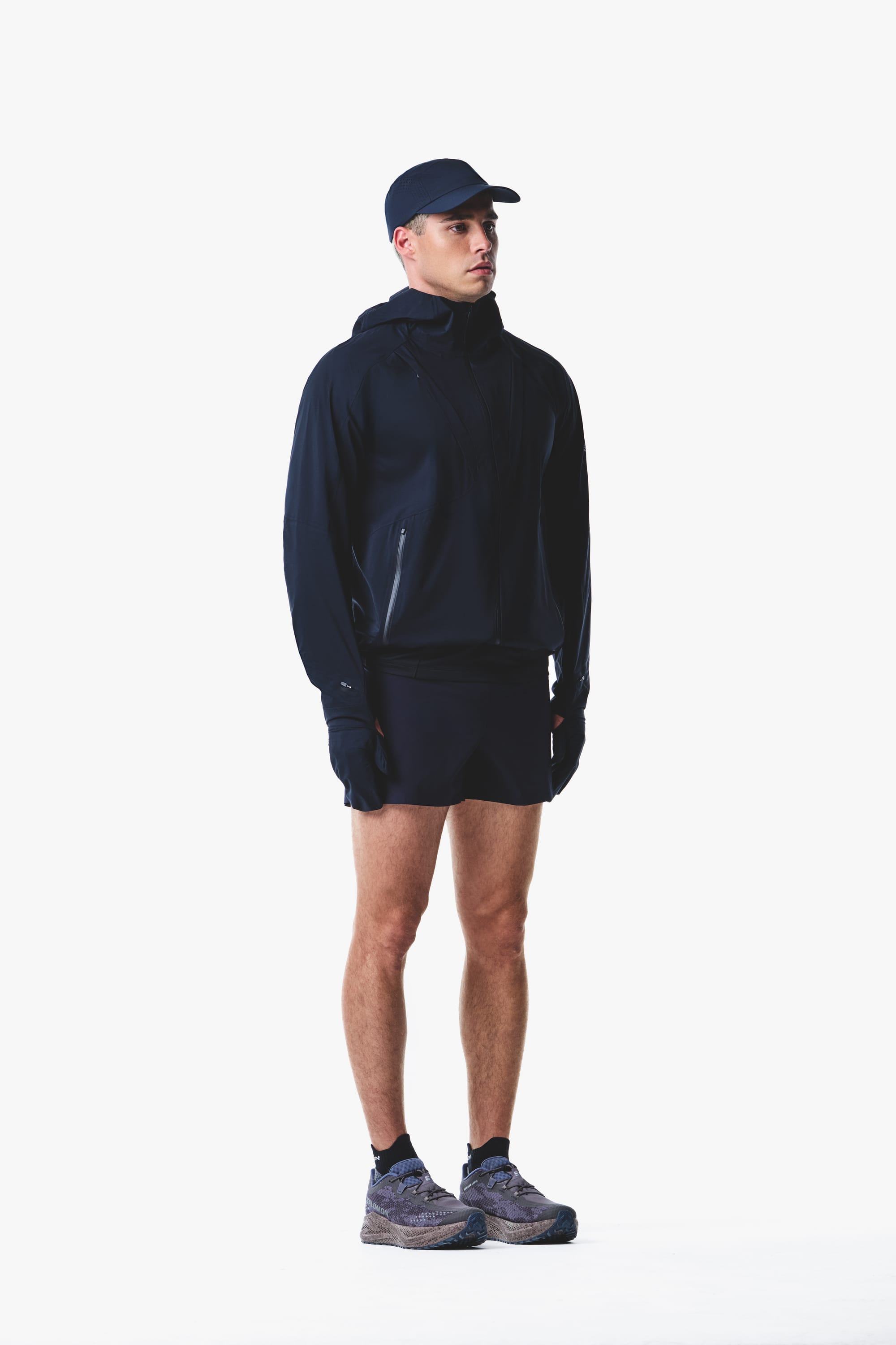 Salomon men's Autumn/Winter 2026 dark navy hooded trail-running jacket and shorts, three-quarter view.