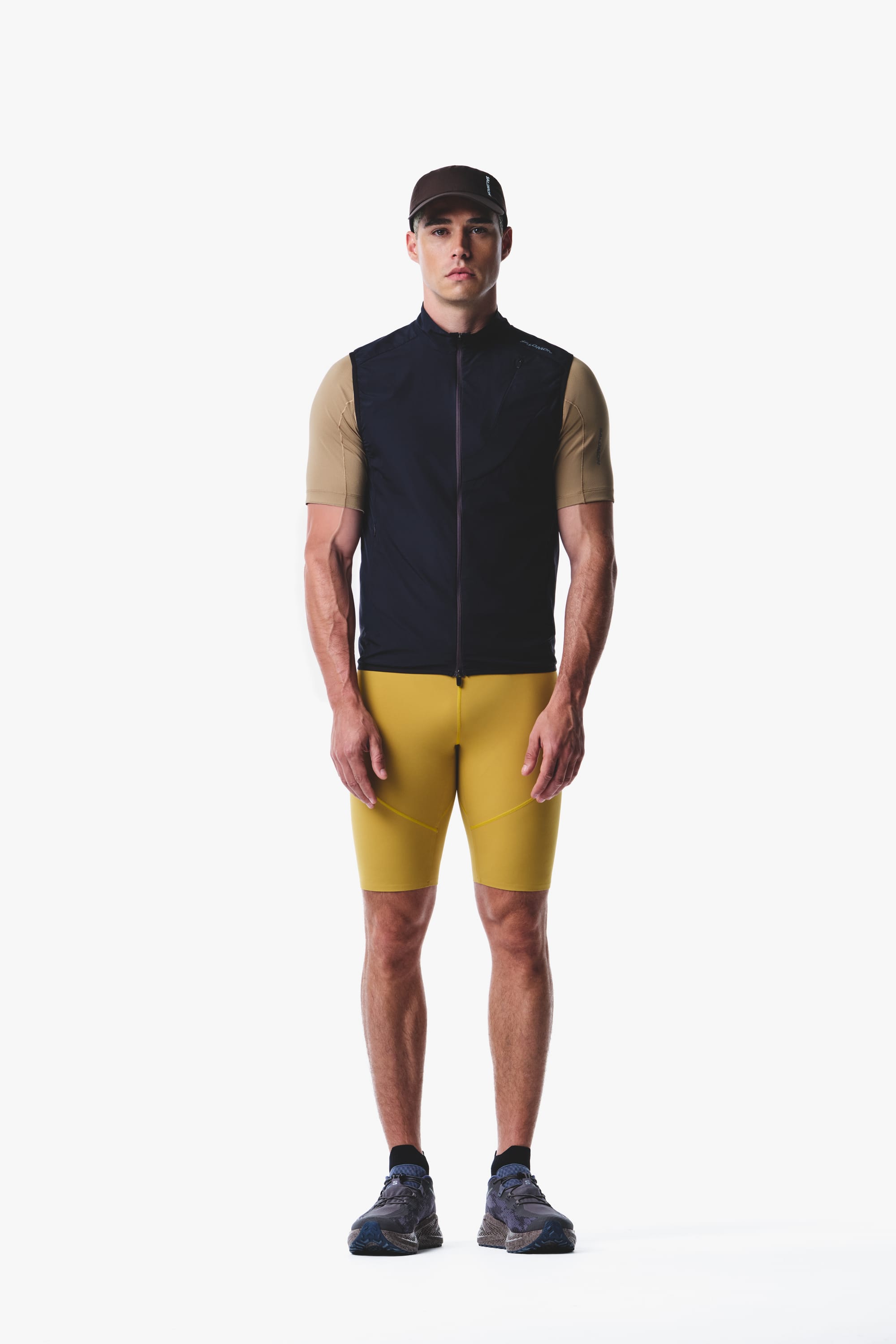 Salomon men's Autumn/Winter 2026 dark sleeveless running vest and yellow fitted shorts, front view.