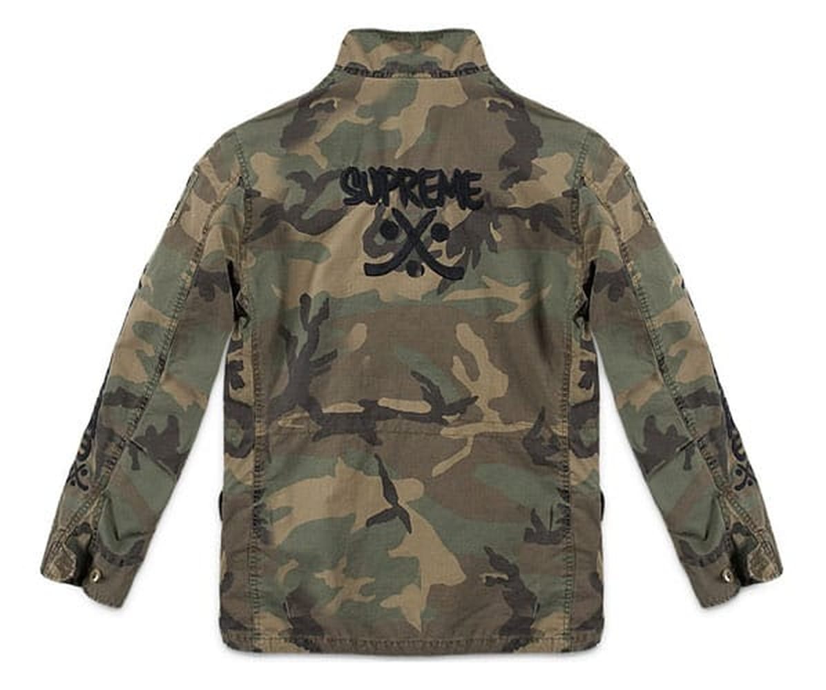 Back of the Supreme x WTAPS Spring 2007 M-65 jacket in woodland camouflage with the large black Supreme crossed-bones logo.