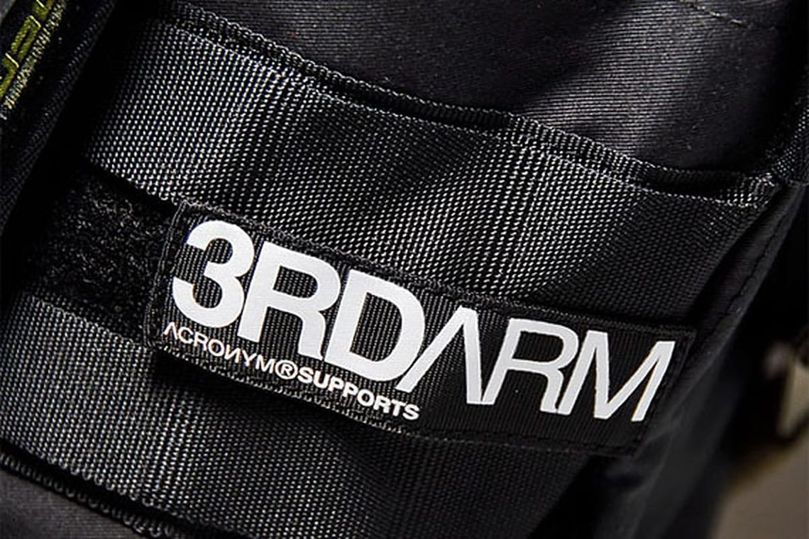 Acronym 3RD ARM label detail on black technical webbing.