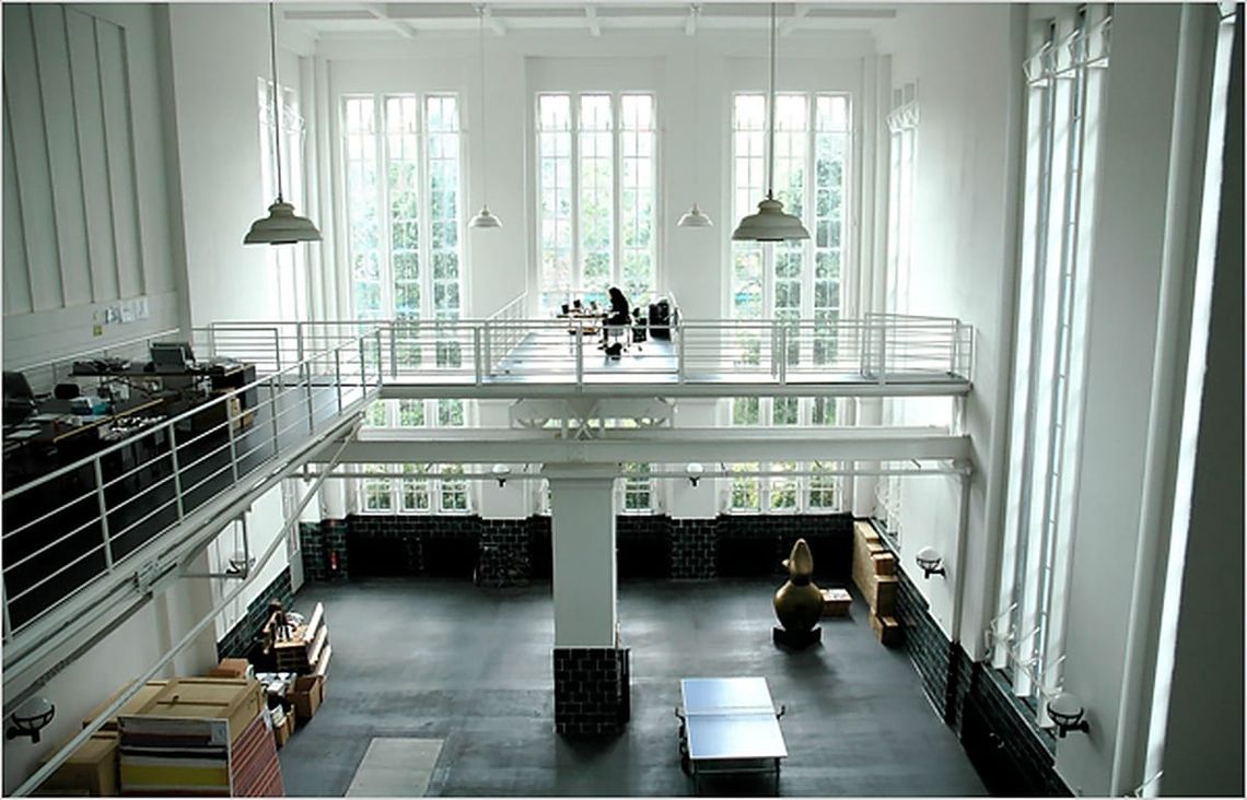 Converted Neukölln water-pumping station interior with white mezzanine walls and tall industrial windows.