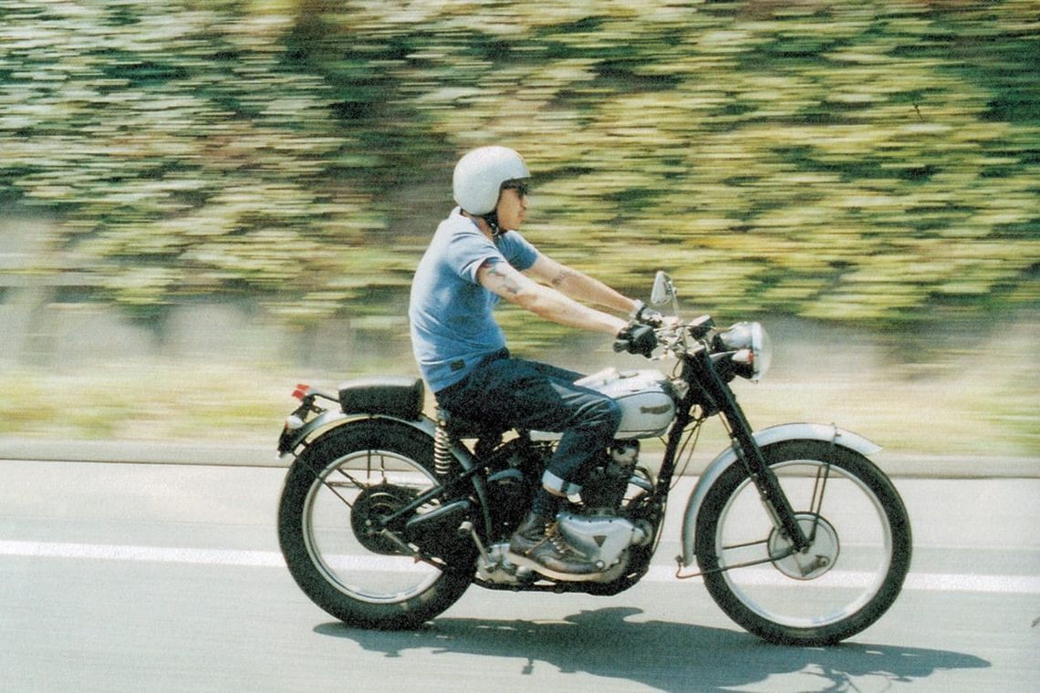 WTAPS FW13 Lifist lookbook image of Tetsu Nishiyama riding a vintage motorcycle in a blue shirt and white helmet.