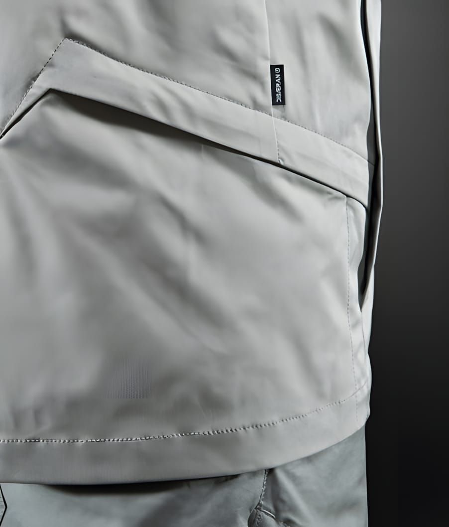 Close-up of grey Nike Tech Woven pants showing slash pocket detail and Nike label, Dark Plaster colorway.