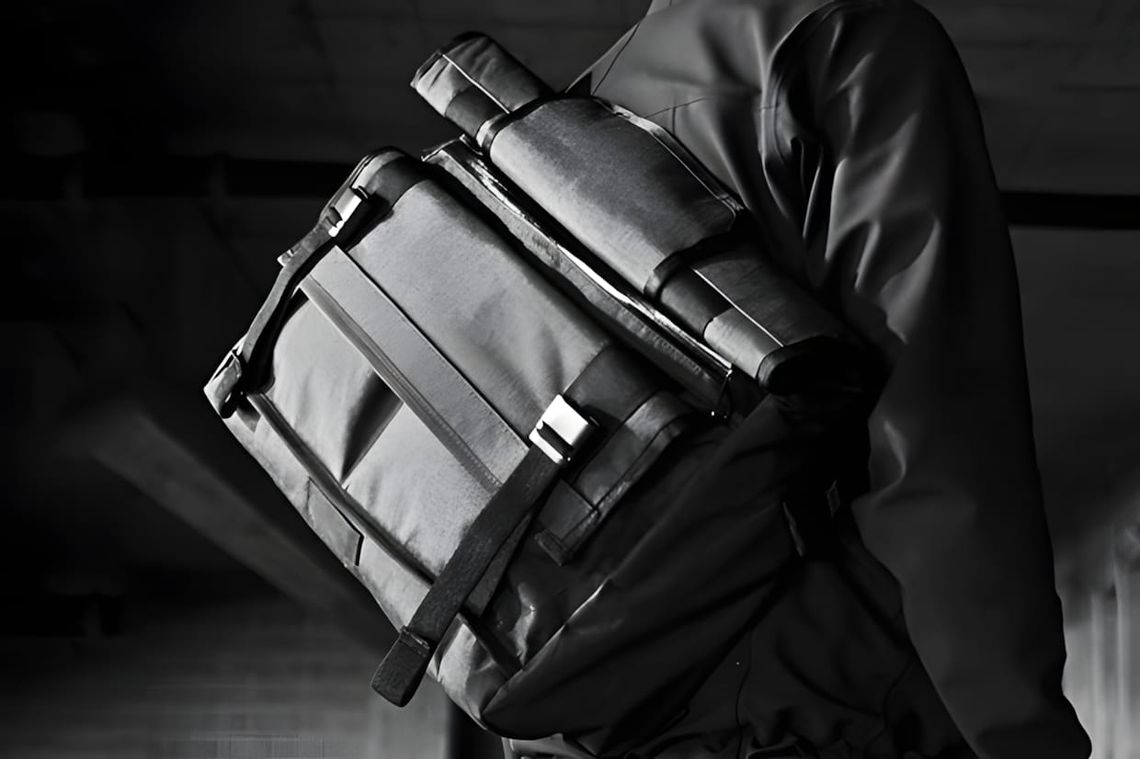 Person wearing a Mission Workshop AP Series VX messenger bag with compression straps and buckle closure, B&W photo.