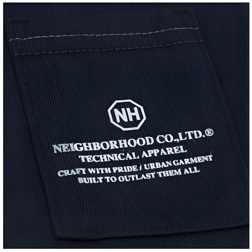 Close-up of Neighborhood Co.,Ltd. woven garment label with NH logo and 'Built to Outlast Them All' text on dark navy ground.