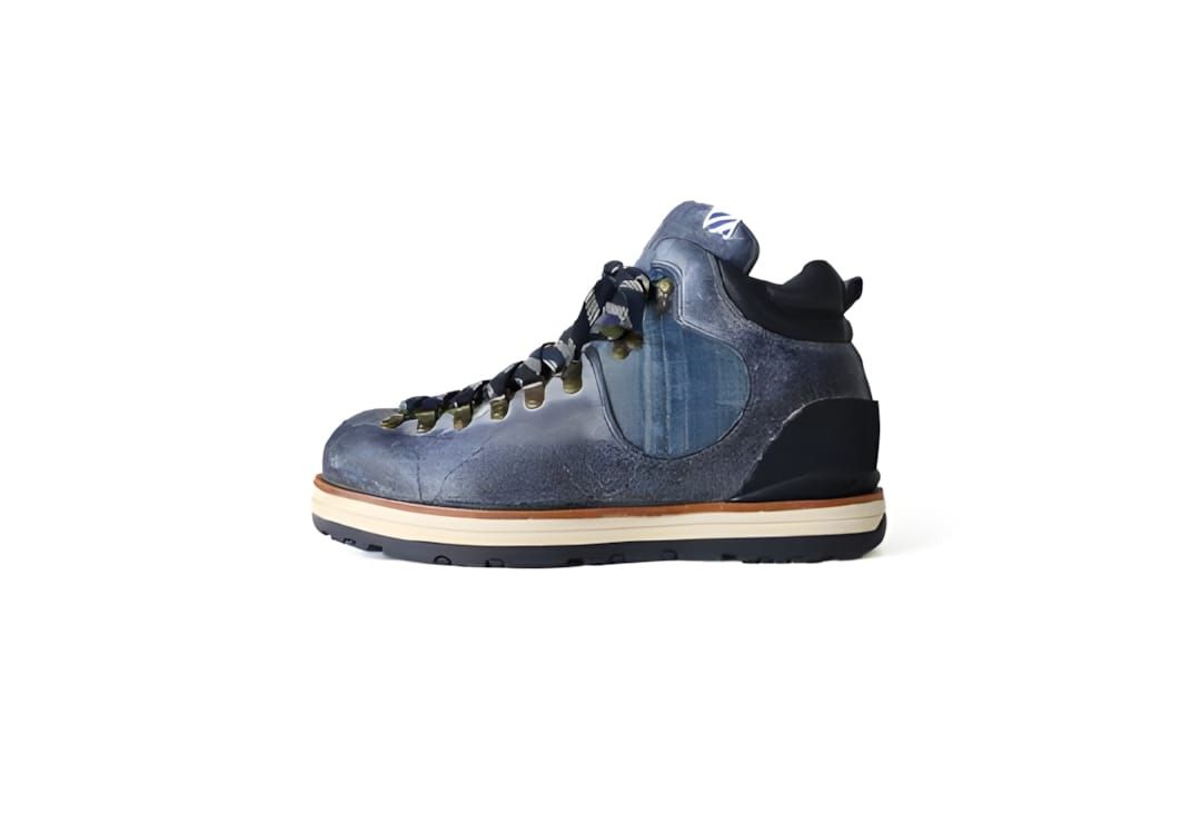 Visvim Serra Boot in navy indigo denim upper with tanned leather trim, brass eyelets, and cream lugged sole, lateral view.