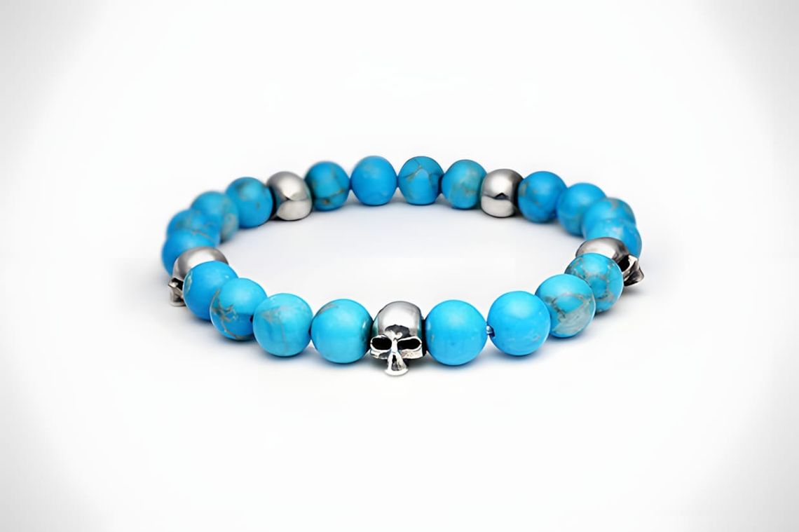 JAM HOME MADE stretch bracelet with turquoise stone beads and sterling silver skull charms on a white background.