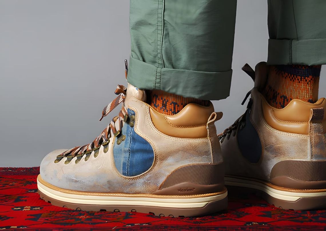 On-feet shot of the Visvim Serra Boot AW2011 in tan waxed leather with an indigo denim side panel, chunky cream Vibram lug so