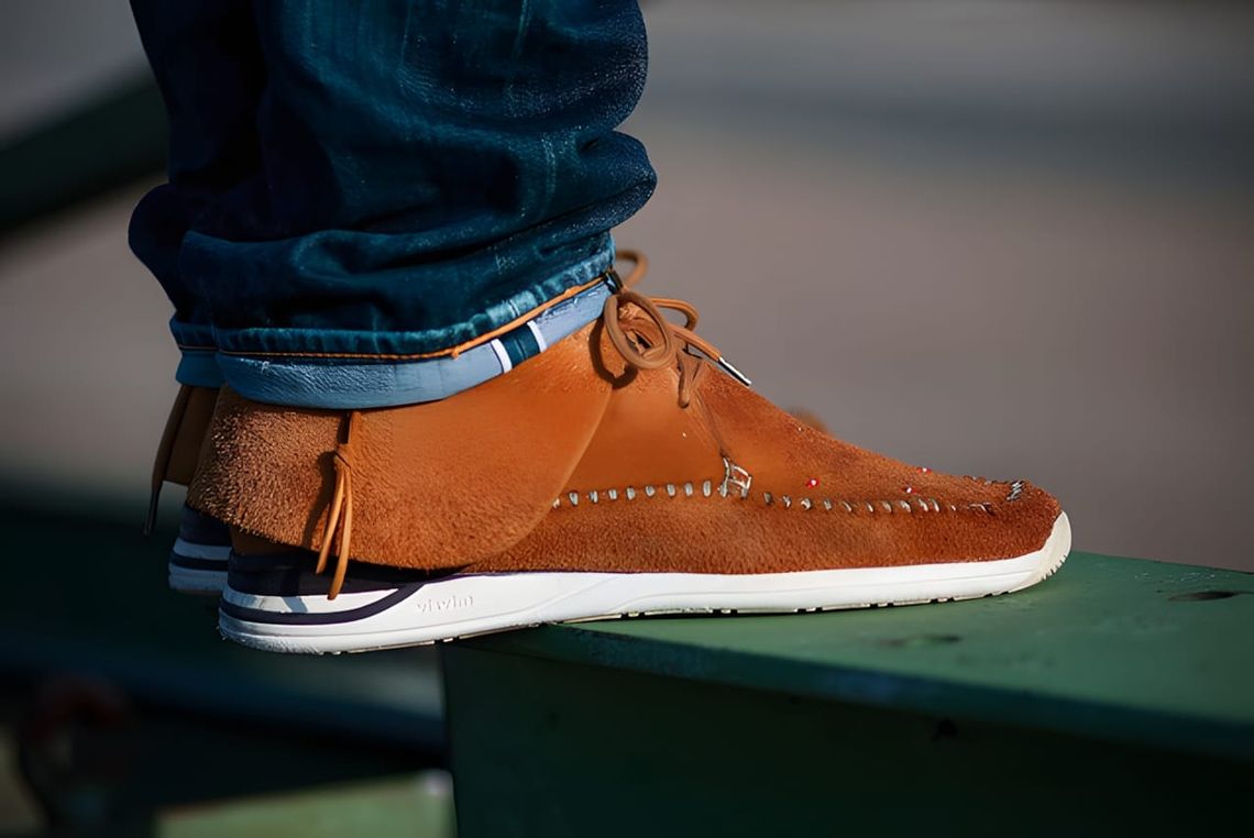 Visvim FBT Lhamo-Folk sneakers in dark brown buckskin, showing hand-sewn moccasin toe construction with bead detailing and Vi