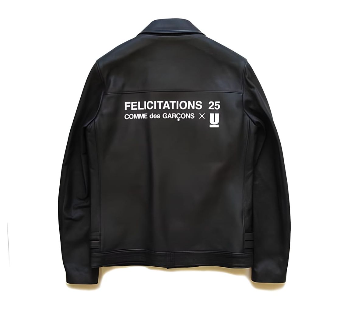 Back of black leather jacket with white printed text reading FELICITATIONS 25 COMME des GARÇONS × Undercover