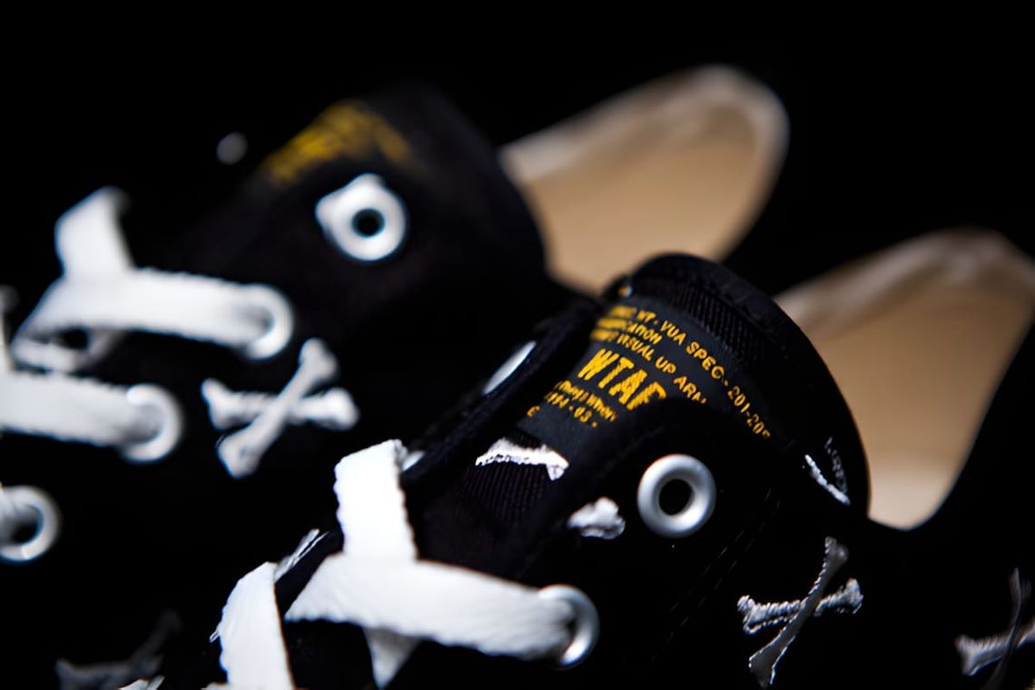 WTAPS Crossbones black low-top canvas sneaker with all-over embroidered crossbones monogram, white laces, and WTAPS tongue la