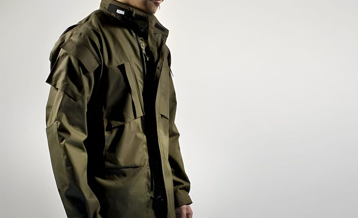 Stone Island Shadow Project olive technical field jacket with stand collar and large patch pockets, side-front view.