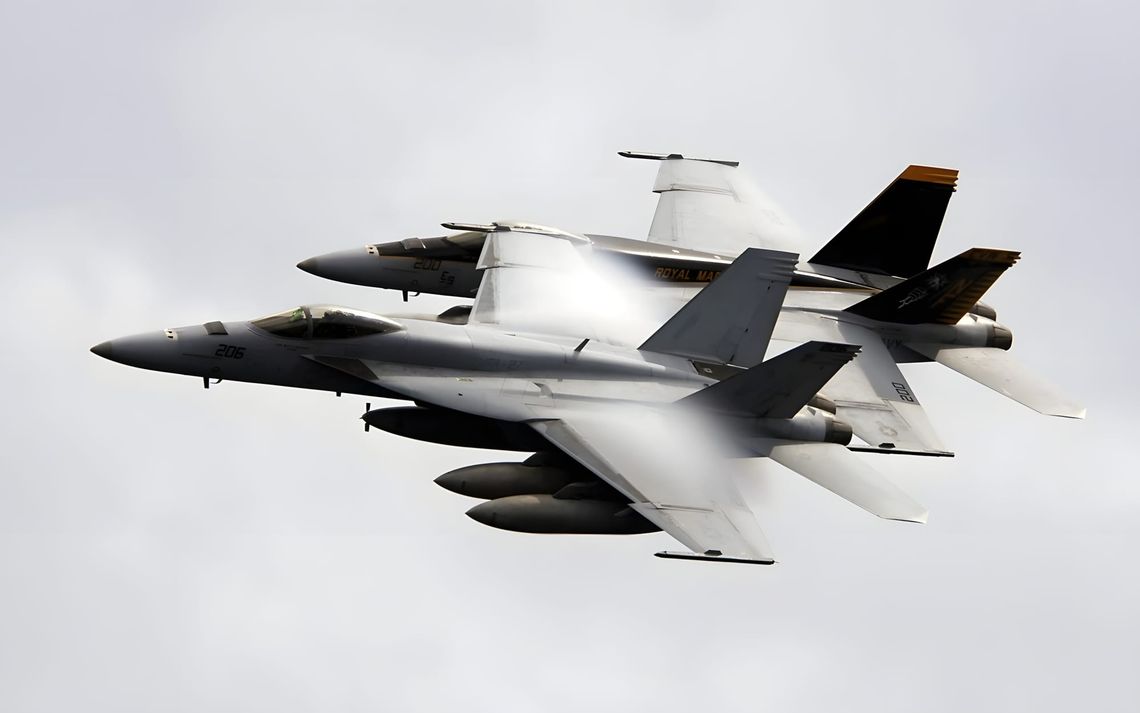 Two VFA-27 Royal Maces F/A-18E Super Hornets in close formation, transonic vapor condensation visible, modex 200 and 206.