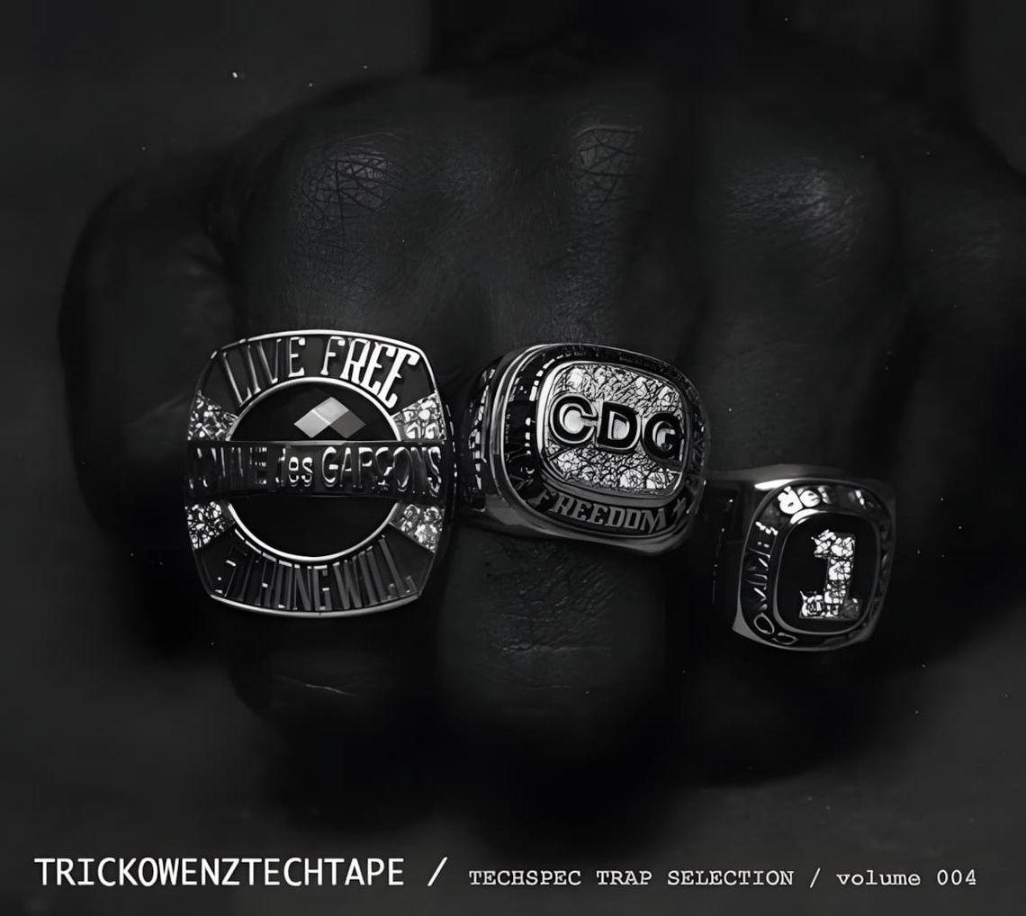 Black-and-white fist shot wearing three championship-style rings; center ring reads CDG FREEDOM, left reads LIVE FREE COMME d