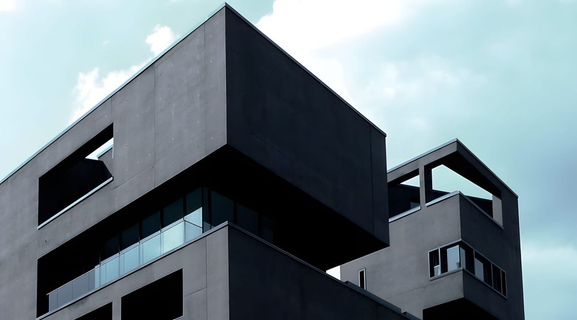 Low-angle view of Linienstrasse 40 in Berlin-Mitte: a dark exposed-concrete residential building with strong cantilevered upp