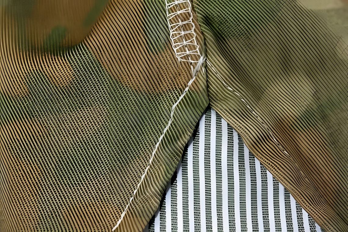 Close-up of a WWII USMC M1 helmet cover showing the P1942 frogskin camouflage fabric — tan base with irregular green and brow