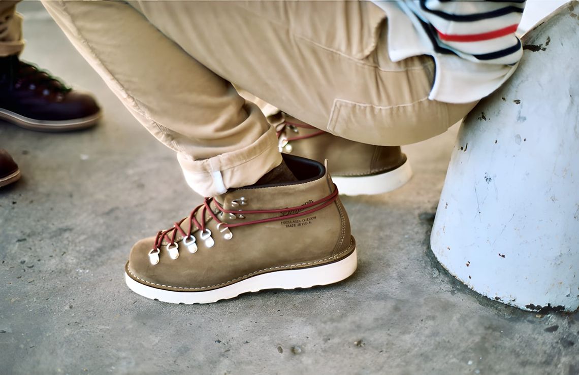 Worn-on-feet close-up of a Danner Mountain Light hiking boot in tan suede with red flat laces, white barrel lace locks, white