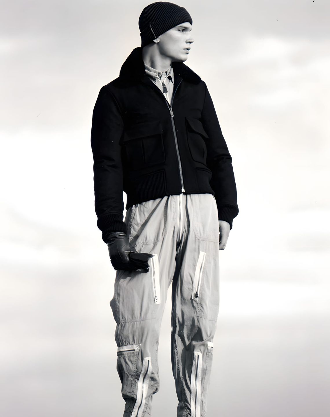 Male model Shawn photographed outdoors against an overcast sky in black and white by Katsuhide Morimoto. He wears a black bom