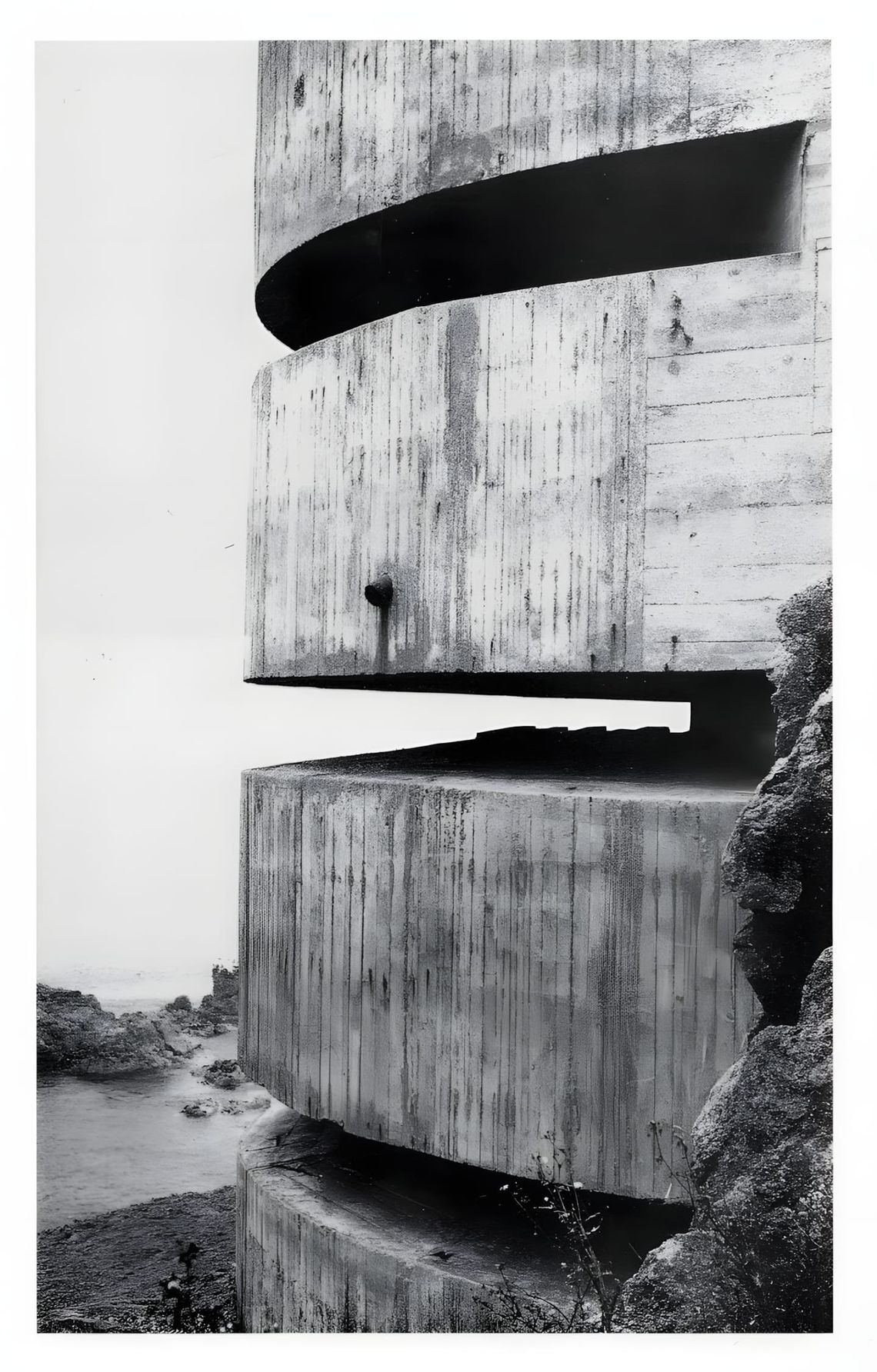 Black-and-white photograph of a massive stacked-slab concrete WWII bunker on the French Atlantic coast; board-formed concrete