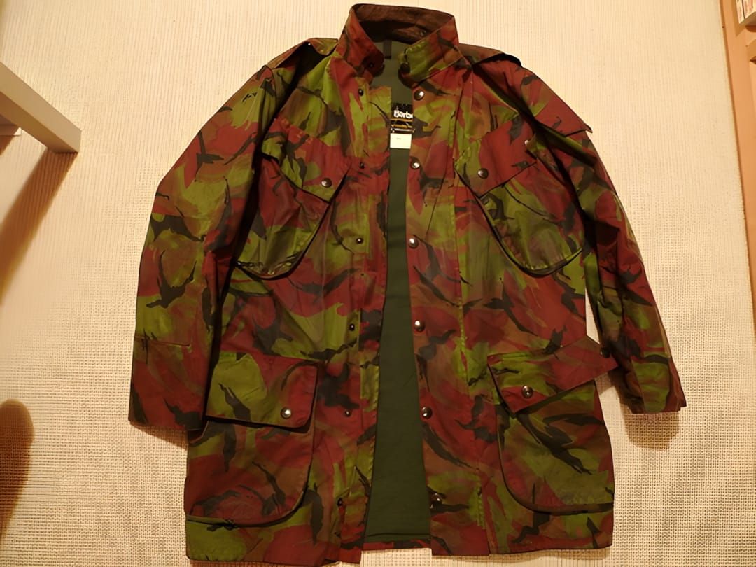 Flat-lay of a vintage 1980s Barbour 'The Military' waxed-cotton jacket in British DPM camouflage — large irregular green, oli