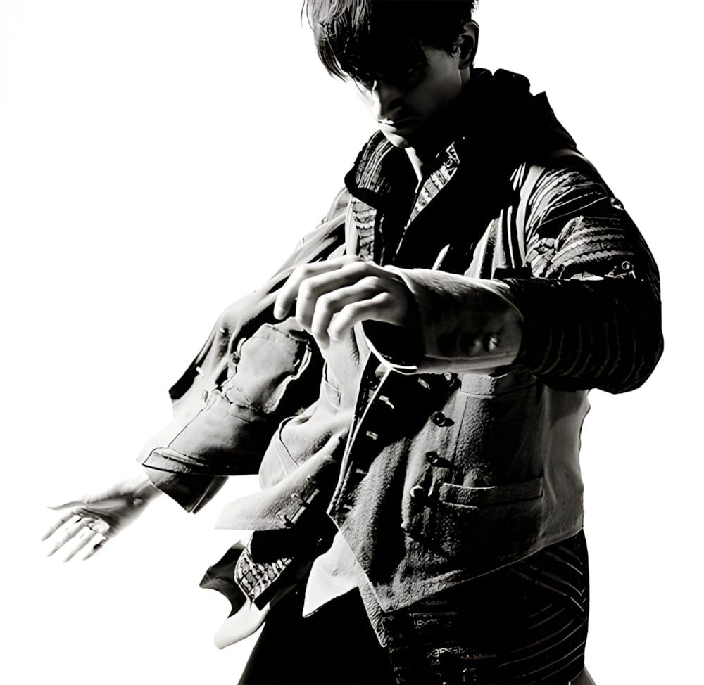 Male model in a layered, distressed multi-pocket cotton jacket shot in B&W against a white ground; dynamic mid-gesture pose, 