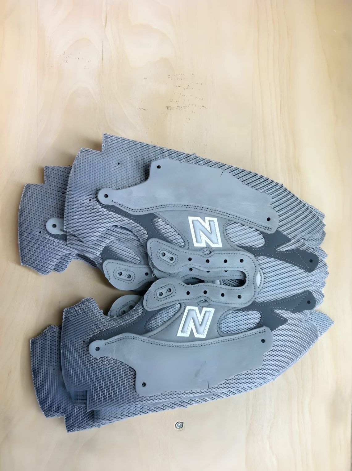 Overhead top-down view of a pair of grey New Balance 992 (M992GR) sneakers laid flat on a light wood surface, showing the emb