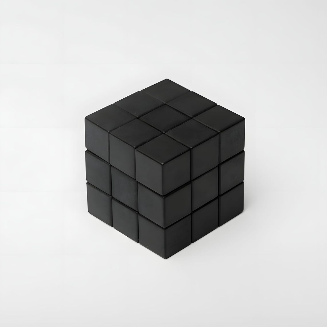 All-black 3x3 Rubik's-style twisty puzzle cube with uniform matte black facets on all sides, photographed on a light grey sea