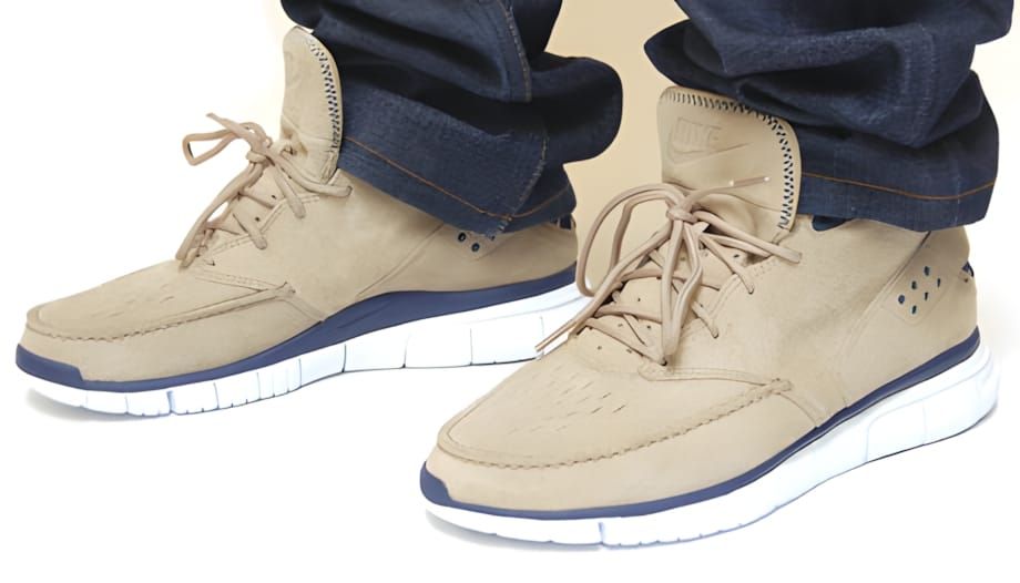 Tan suede Nike Free Hybrid Boot Premium worn on feet with raw selvedge denim, showing perforated toe box, navy accent trim at