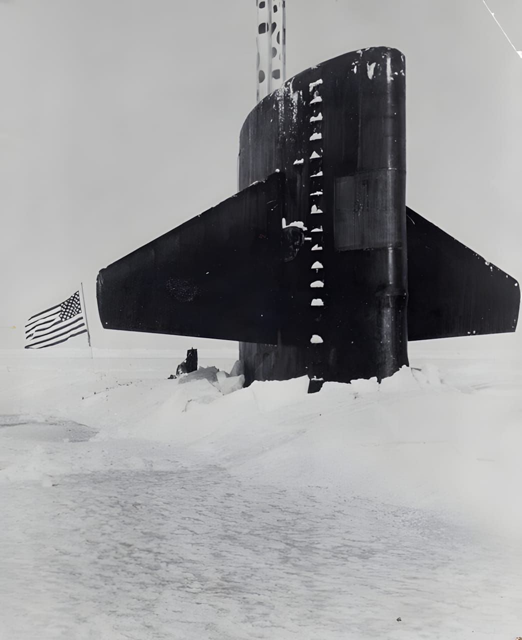 Black-and-white photograph of USS Skate (SSN-578) surfaced through broken Arctic pack ice at the North Pole, 1959. The connin