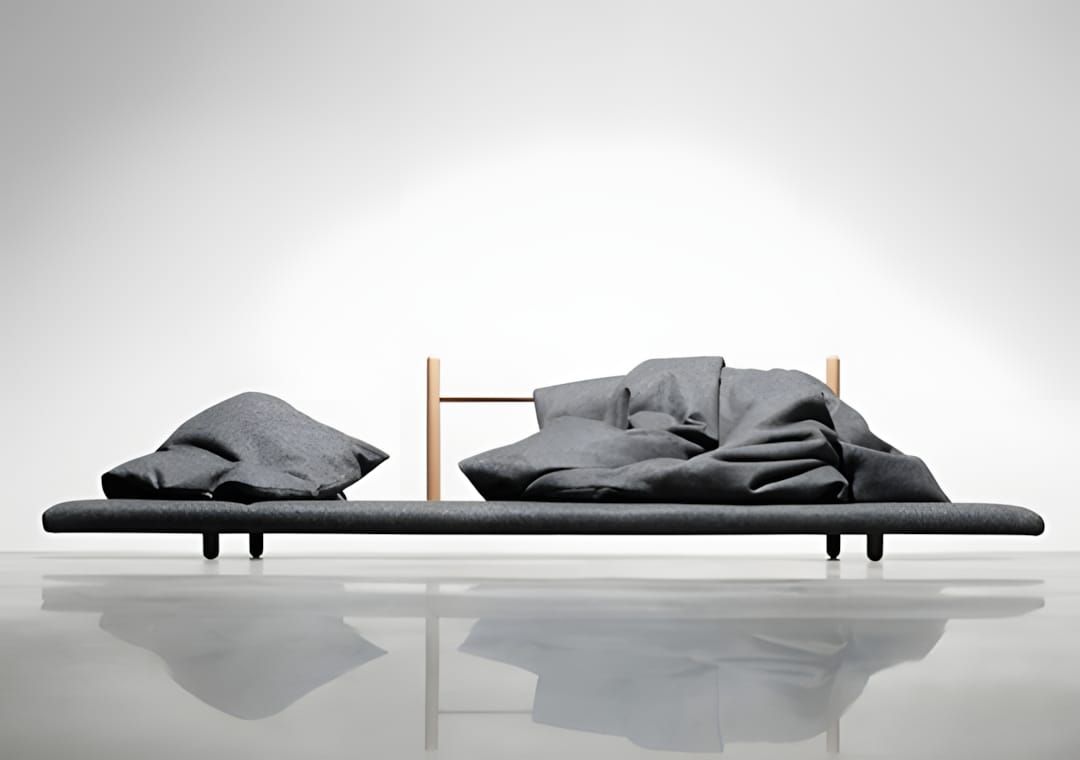Low minimal oak platform daybed with two thin vertical wooden uprights and charcoal grey wool cushions and duvets draped loos