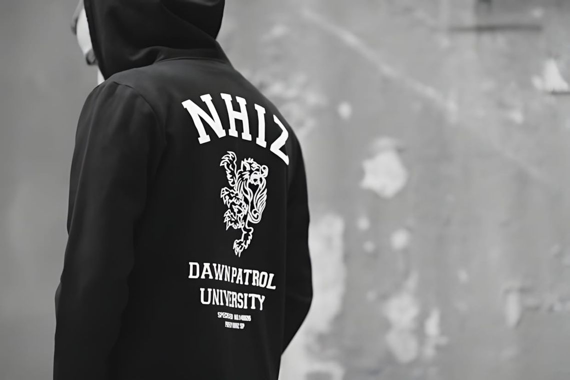Person from behind wearing a black pullover hoodie with collegiate arch 'NHIZ' lettering, a rampant heraldic lion graphic, an