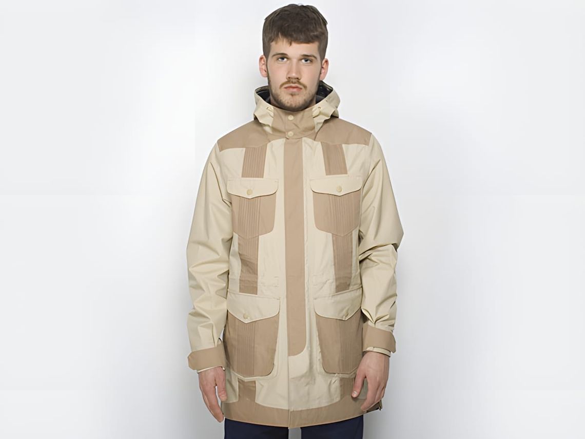 Male model wearing a cream and tan Marshall Artist mid-length hooded jacket with alternating ripstop and ribbed fabric panels