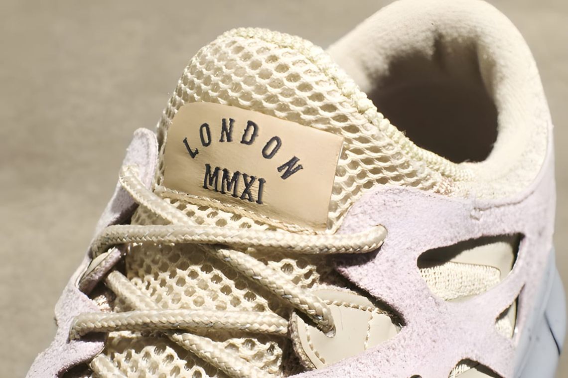 Close-up of the Nike Free Run+ 2 QS 'London MMXI' tongue, showing a woven tan canvas label embroidered with 'LONDON MMXI' in 