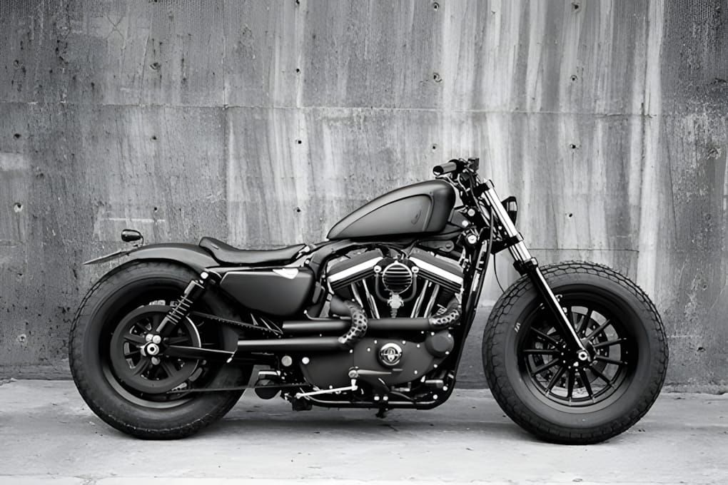 Blacked-out Harley-Davidson Sportster bobber in profile against concrete wall, B&W.