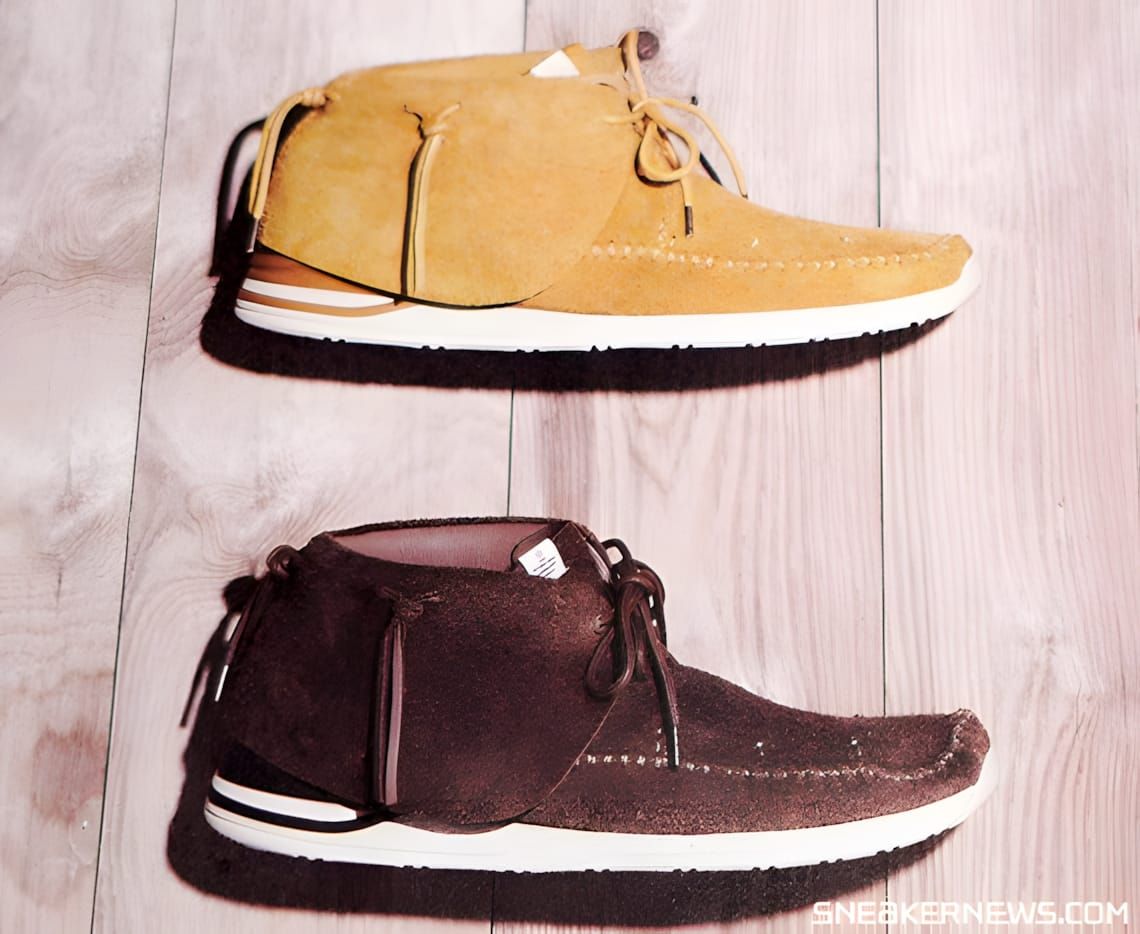 Visvim FBT JP moccasin sneakers in camel suede (top) and dark brown suede (bottom) on a wood-plank surface.