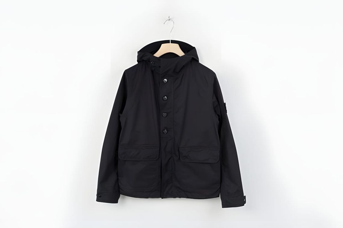 Stone Island Ventile Ghost Piece hooded jacket — a pale-toned cotton shell with concealed seams, a packable hood, and the Gho