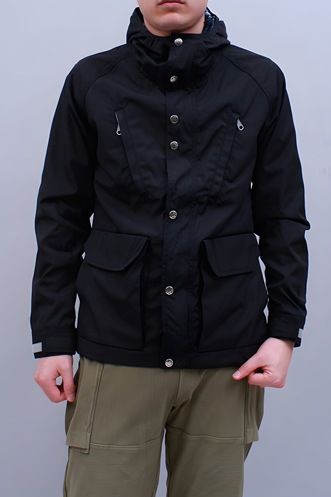 Nanamica black Cruiser Jacket with snap storm placket, chest zip pockets, bellows patch pockets, and packable hood.