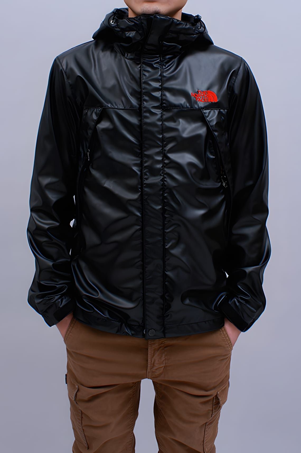 The North Face Purple Label glossy coated-black nylon zip mountain wind jacket, shown front-on on a male model, with a red em