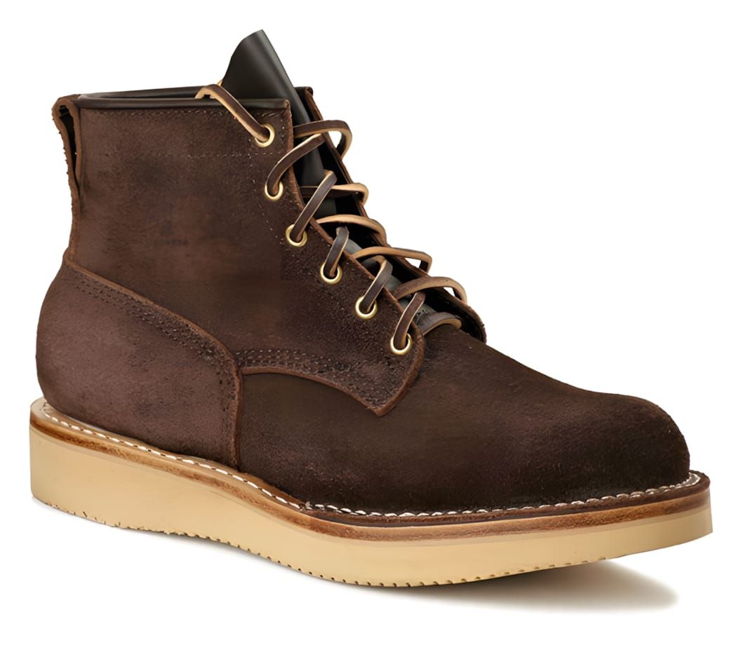 Viberg Bobcat work boot in dark brown roughout suede, five-eyelet lace-up with brass eyelets and tan waxed laces, on an off-w