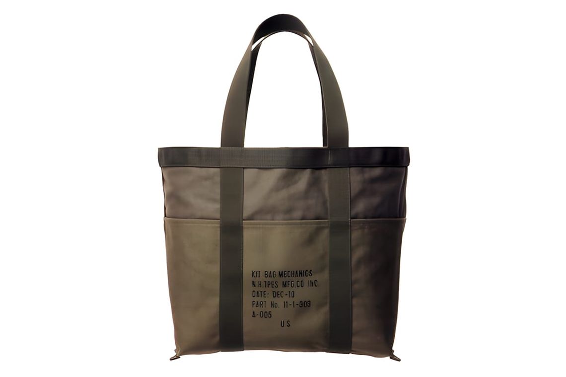 Olive canvas open-top tote with stencil text 'KIT BAG MECHANICS / N.H.TPES MFG.CO. INC.' and external side pockets