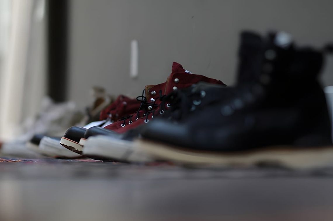 Row of visvim boots lined up on a kilim rug at the LA Trunk Show: burgundy Virgil Boots-Folk in the foreground, dark navy pai
