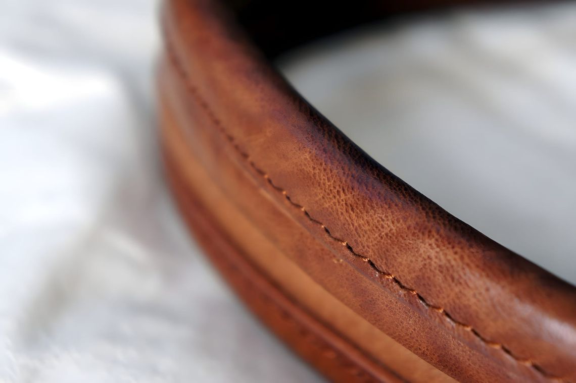 Macro close-up of visvim Homer Tote tan leather handle showing saddle stitching detail.