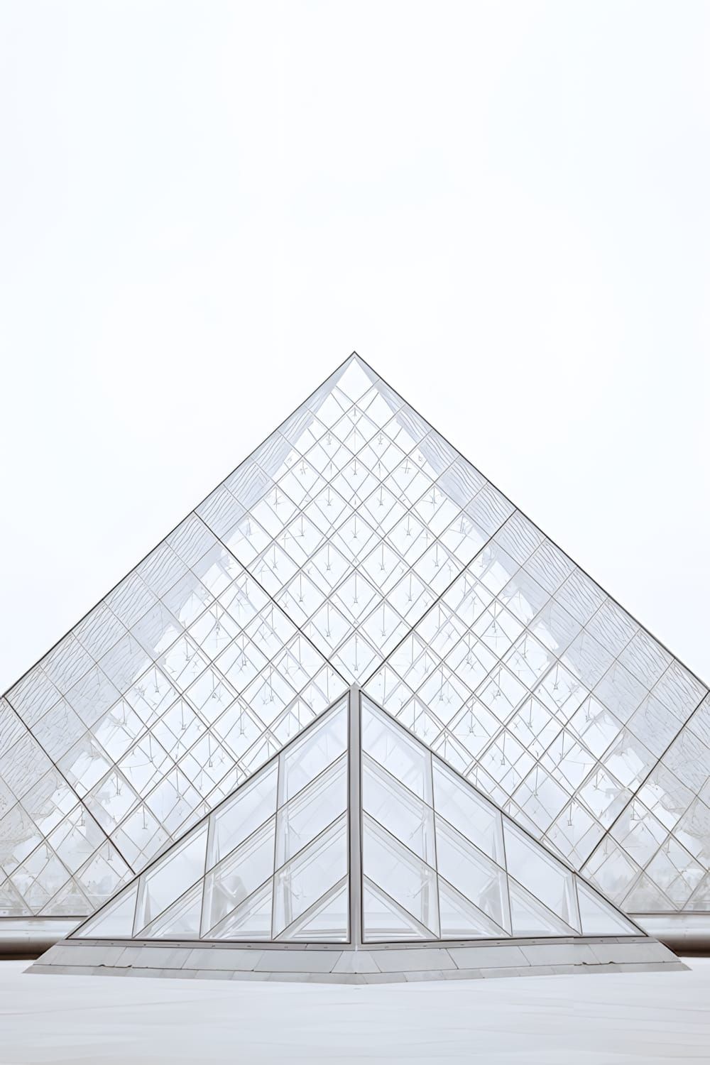 Low-angle view of the Louvre Pyramid — a large glass and steel geodesic pyramid set in the courtyard of the Louvre Museum, Pa