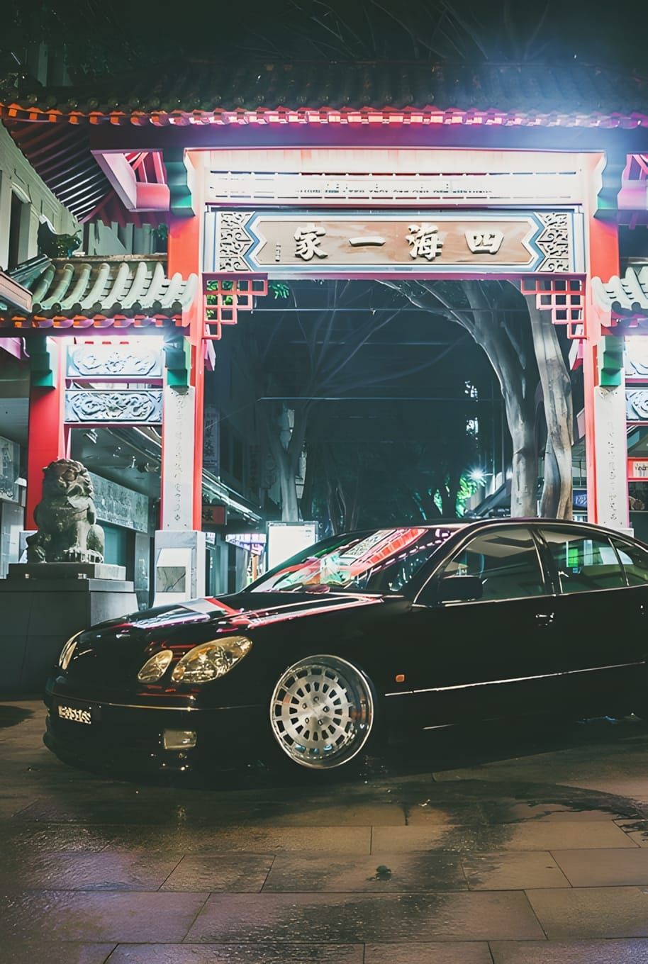 Black Lexus GS sedan with chrome multi-spoke aftermarket wheels parked at night in front of the Sydney Chinatown ceremonial p