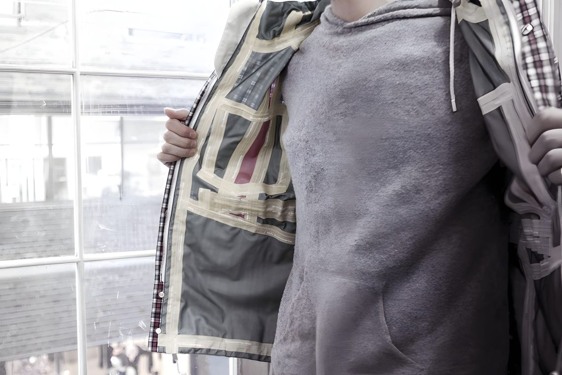 Interior view of a Visvim PFD GORE-TEX jacket in a plaid check pattern, held open to show taped seams and plaid lining, worn 