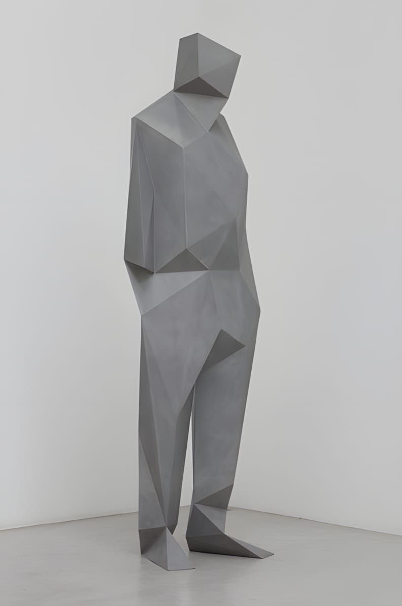 Large-scale grey faceted low-polygon standing male figure sculpture in a white gallery space, by Xavier Veilhan. The figure i
