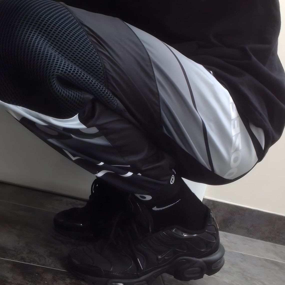 Nike Air Max Plus TN in Triple Black colorway (604133-050), side profile showing black mesh upper, TPU arch fins, and black A