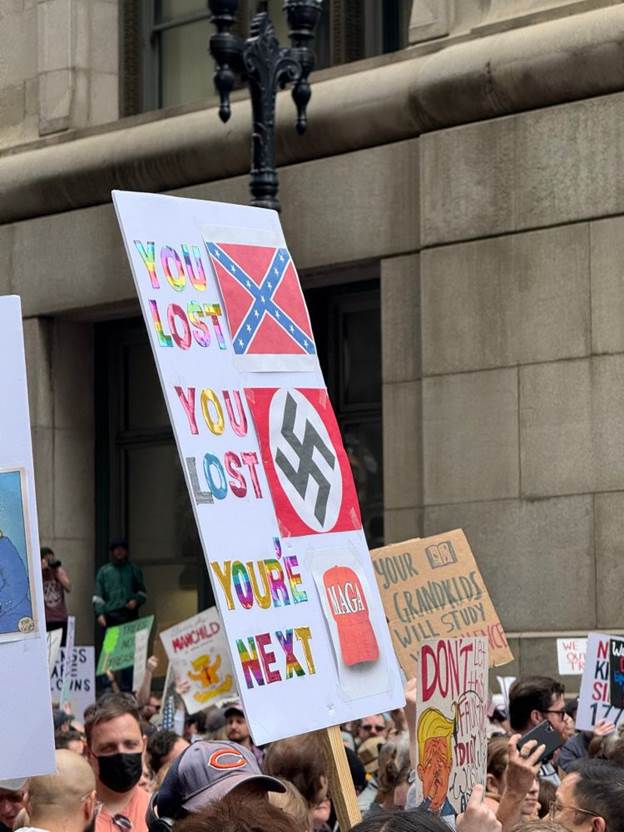 Sign with rainbow lettering:

YOU LOST (next to Confederate flag)

YOU LOST (next to Nazi flag)

YOU’RE NEXT (next to M*GA hat)